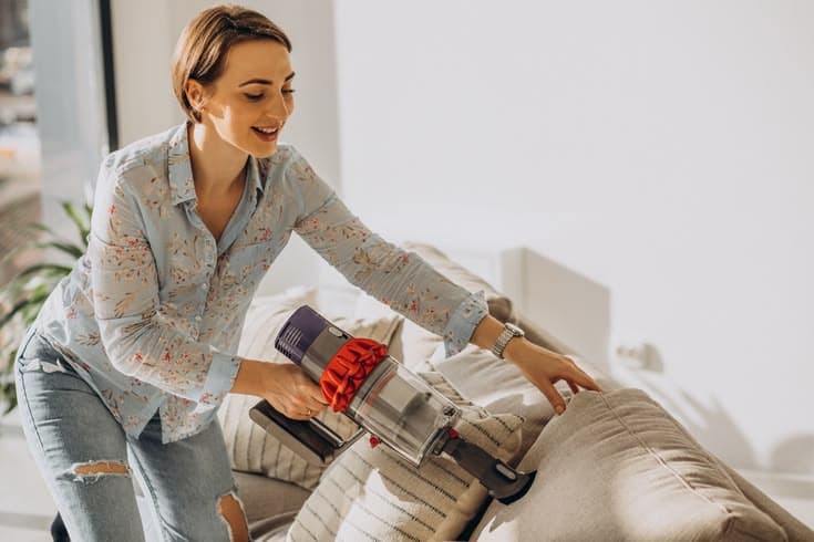 Two cleaners dusting and washing the windows of a living room